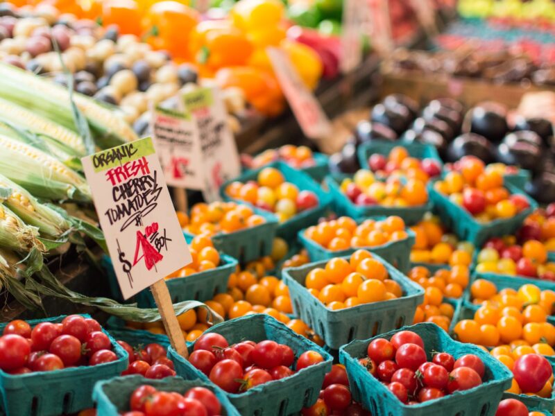 Small baskets of red and yellow cherry tomatoes arranged on a table at a farmers' market.
