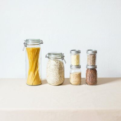 Glass jars filled with various kitchen staples against a white background.